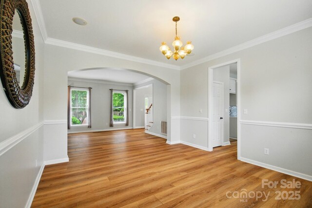 138 Montibello Dr, Mooresville, NC 28117 - empty room featuring arched walkways, a chandelier, light wood-style flooring, ornamental molding, and baseboards