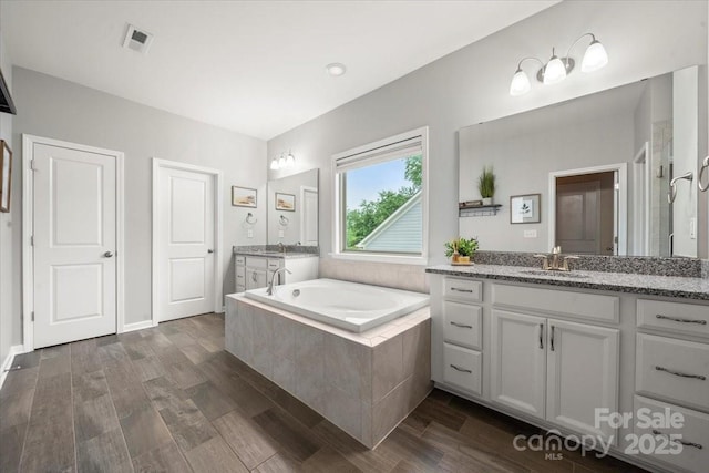 9530 Hightower Oak St, Huntersville, NC 28078 - bathroom featuring two vanities, a bath, and wood finished floors