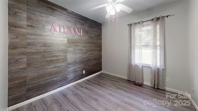 2026 Willow Ridge St, Conover, NC 28613 - spare room featuring wooden walls, ceiling fan, wood finished floors, and baseboards