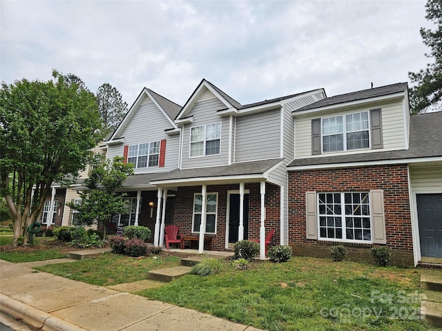 7562 Petrea Ln, Charlotte, NC 28227 - view of front of house with brick siding, a porch, a front yard, and a shingled roof