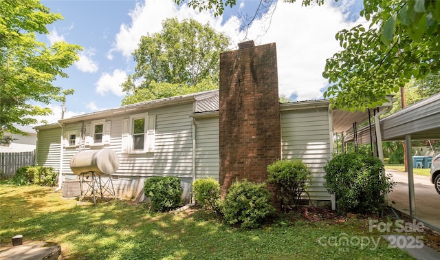 1463 Land St, Lenoir, NC 28645 - back of house featuring a chimney, a lawn, and a carport