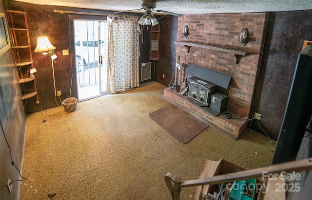 1463 Land St, Lenoir, NC 28645 - living area featuring a wood stove, a ceiling fan, carpet flooring, a textured ceiling, and brick wall