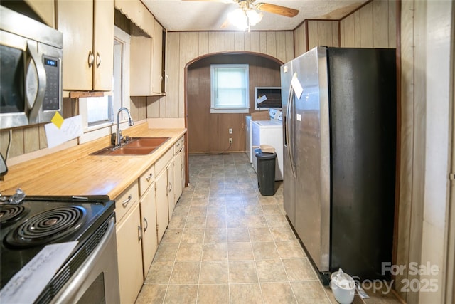 1463 Land St, Lenoir, NC 28645 - kitchen with stainless steel appliances, a sink, washer and dryer, wooden walls, and a ceiling fan
