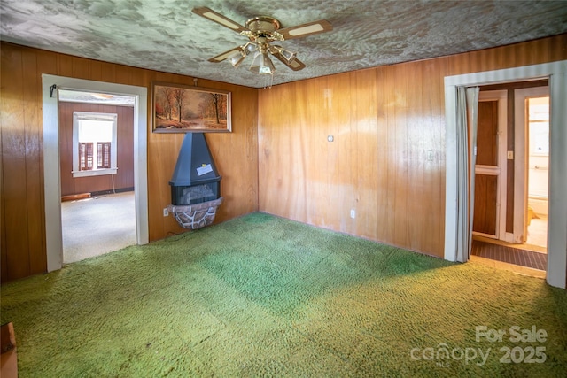 1463 Land St, Lenoir, NC 28645 - carpeted empty room featuring ceiling fan, wooden walls, and a wood stove