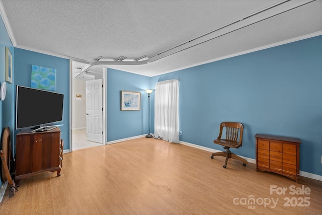 unfurnished room featuring a textured ceiling, wood finished floors, crown molding, and baseboards