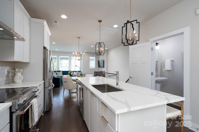 kitchen featuring a sink, appliances with stainless steel finishes, a chandelier, a center island with sink, and open floor plan
