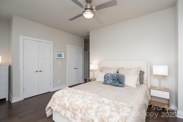 bedroom featuring multiple closets, dark wood-style flooring, baseboards, and a ceiling fan