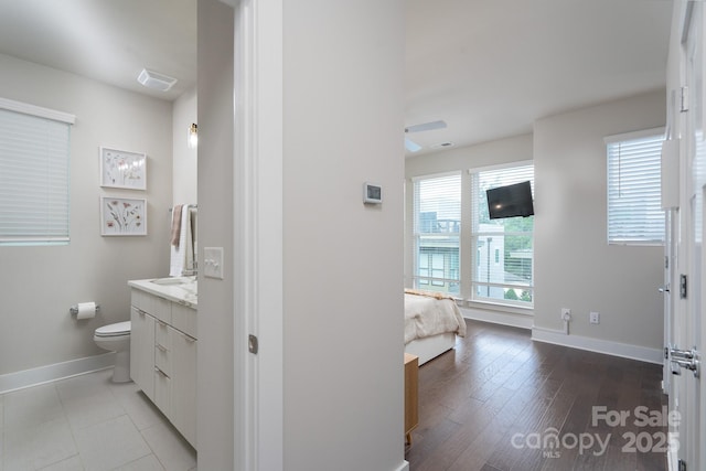 bathroom featuring baseboards, vanity, toilet, ensuite bathroom, and wood finished floors