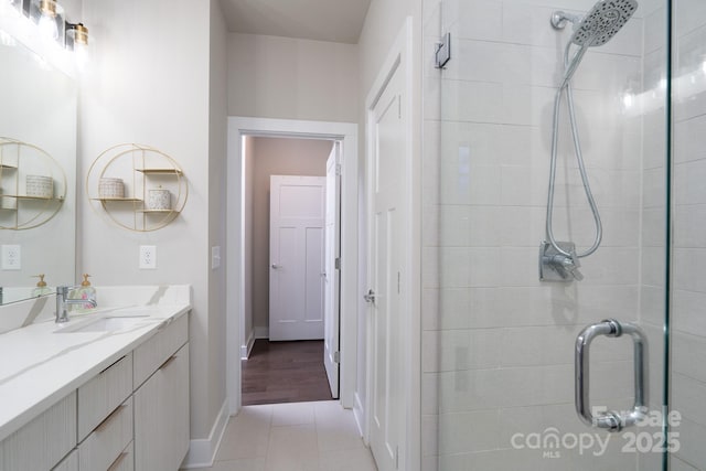 full bathroom with a shower stall, vanity, baseboards, and tile patterned floors