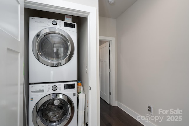 laundry room with stacked washer and clothes dryer, dark wood-style flooring, and baseboards