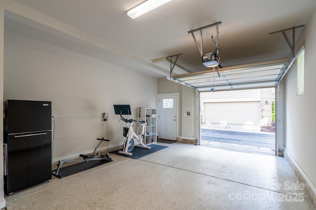garage featuring a garage door opener, freestanding refrigerator, and baseboards