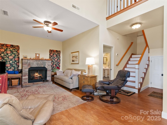 572 Multiflora Way, Waynesville, NC 28785 - living area with wood finished floors, ceiling fan, stairway, a stone fireplace, and a towering ceiling