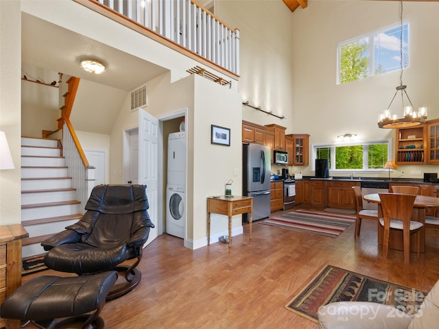572 Multiflora Way, Waynesville, NC 28785 - living room featuring high vaulted ceiling, estacked washer and dryer, light wood-style flooring, a chandelier, and stairway