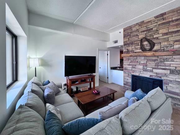 303 Sugar Top Dr Unit 2323, Sugar Mountain, NC 28604 - living room featuring a textured ceiling and a fireplace