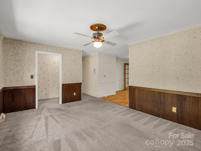 646 Terry Rd, Ellenboro, NC 28040 - unfurnished room with wainscoting, ceiling fan, wooden walls, wallpapered walls, and carpet floors