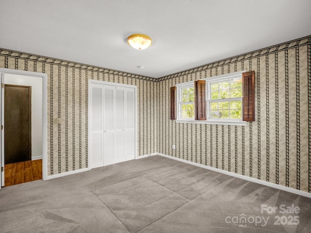 646 Terry Rd, Ellenboro, NC 28040 - unfurnished bedroom featuring a closet, carpet floors, wallpapered walls, and baseboards