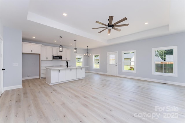 309 Walker St, Kannapolis, NC 28081 - kitchen featuring stainless steel microwave, a raised ceiling, open floor plan, light wood-style floors, and healthy amount of natural light