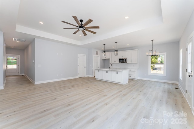 309 Walker St, Kannapolis, NC 28081 - unfurnished living room featuring a tray ceiling, light wood-style floors, a chandelier, ceiling fan, and recessed lighting