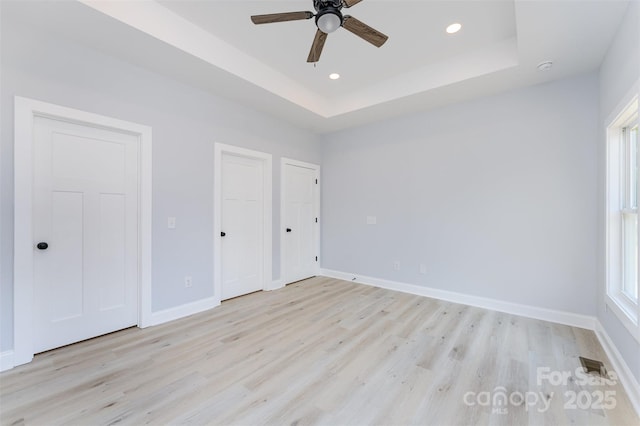 309 Walker St, Kannapolis, NC 28081 - unfurnished bedroom featuring light wood-type flooring, recessed lighting, two closets, a raised ceiling, and ceiling fan