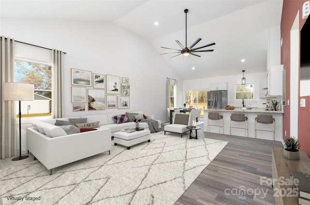 living area featuring light wood-type flooring, a ceiling fan, high vaulted ceiling, and recessed lighting