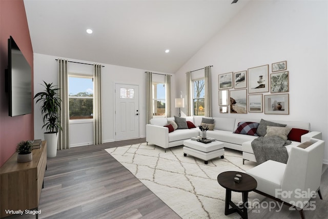 living room featuring plenty of natural light, wood finished floors, recessed lighting, high vaulted ceiling, and baseboards