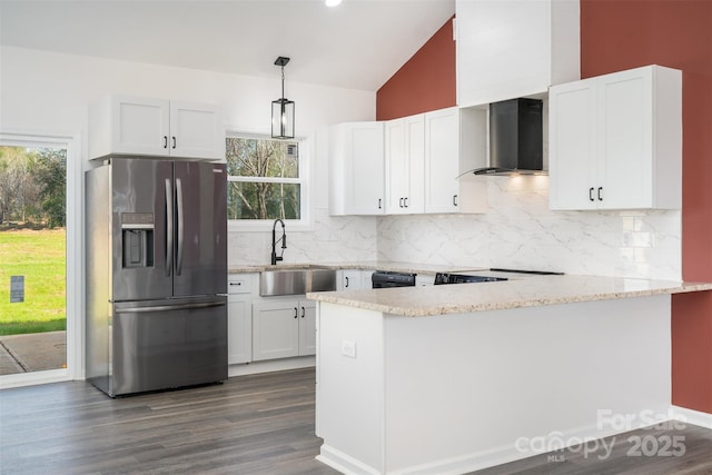 kitchen featuring stainless steel fridge with ice dispenser, wall chimney range hood, a sink, lofted ceiling, and light stone countertops