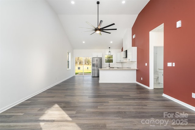 unfurnished living room featuring ceiling fan, high vaulted ceiling, dark wood finished floors, baseboards, and recessed lighting
