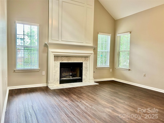 4504 Bellmore Ct, Charlotte, NC 28269 - unfurnished living room featuring dark wood-type flooring, lofted ceiling, plenty of natural light, and a high end fireplace