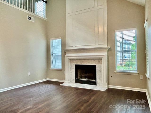 4504 Bellmore Ct, Charlotte, NC 28269 - unfurnished living room with dark wood-style flooring, a high ceiling, plenty of natural light, and a premium fireplace