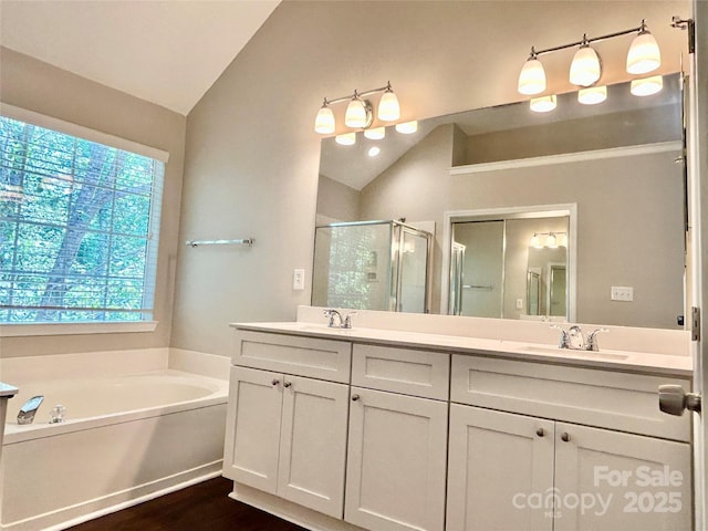 4504 Bellmore Ct, Charlotte, NC 28269 - full bath with vaulted ceiling, a stall shower, double vanity, a bath, and wood finished floors