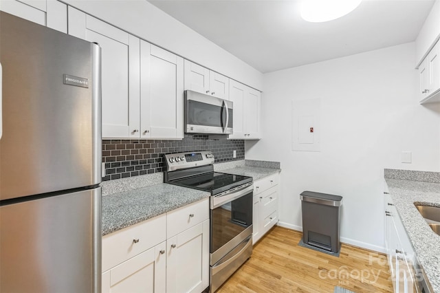 kitchen with stainless steel appliances, tasteful backsplash, light stone countertops, and white cabinets