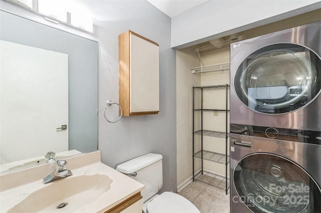 half bathroom with estacked washer and dryer, tile patterned flooring, toilet, baseboards, and vanity