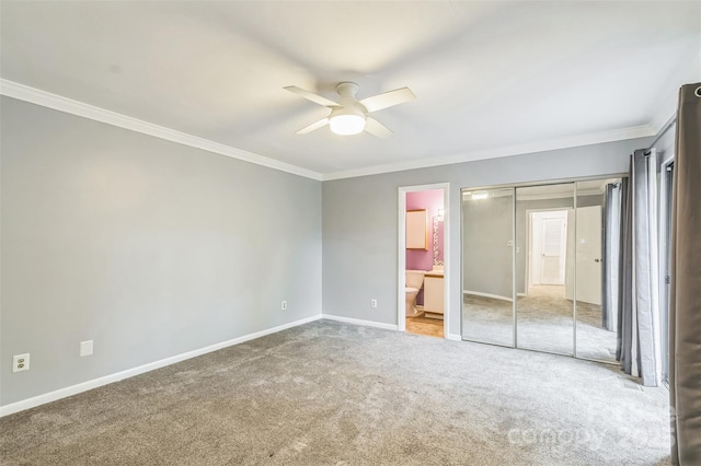 unfurnished bedroom featuring ornamental molding, carpet floors, baseboards, a ceiling fan, and ensuite bath