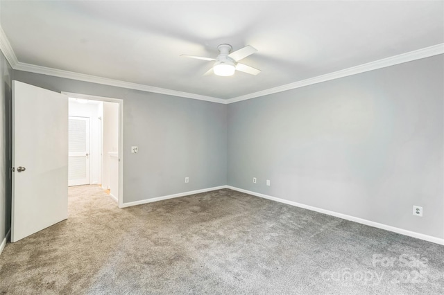 spare room with a ceiling fan, carpet flooring, ornamental molding, and baseboards