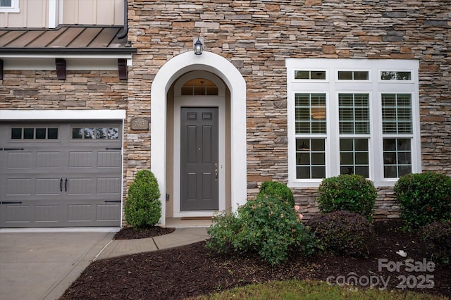 7913 Waverly Walk Ave, Charlotte, NC 28277 - doorway to property featuring stone siding, a standing seam roof, an attached garage, concrete driveway, and metal roof