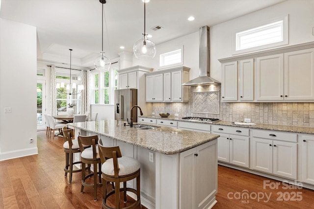 7913 Waverly Walk Ave, Charlotte, NC 28277 - kitchen with a sink, wall chimney range hood, stainless steel appliances, an island with sink, and backsplash