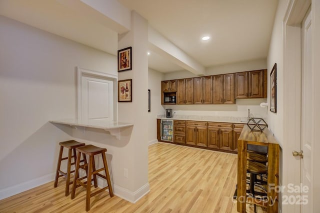 14503 Crest Ct, Charlotte, NC 28278 - kitchen featuring light wood-style flooring, a breakfast bar, black microwave, recessed lighting, and light countertops