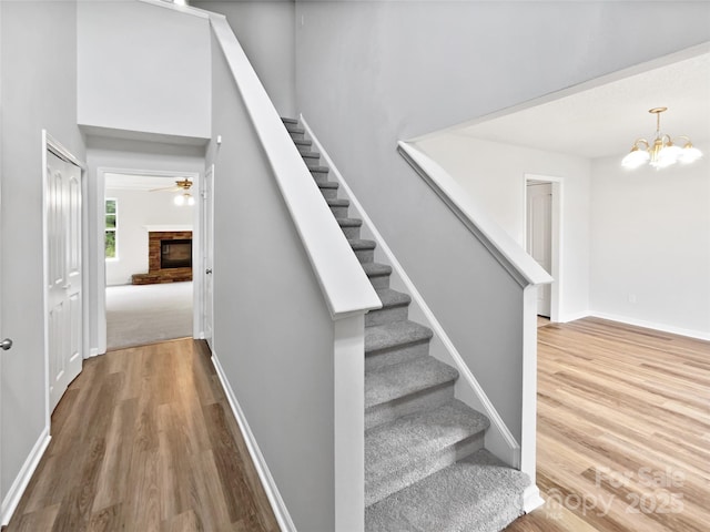 752 Raindrops Rd, Gastonia, NC 28054 - stairway featuring wood finished floors, a fireplace, a chandelier, and baseboards
