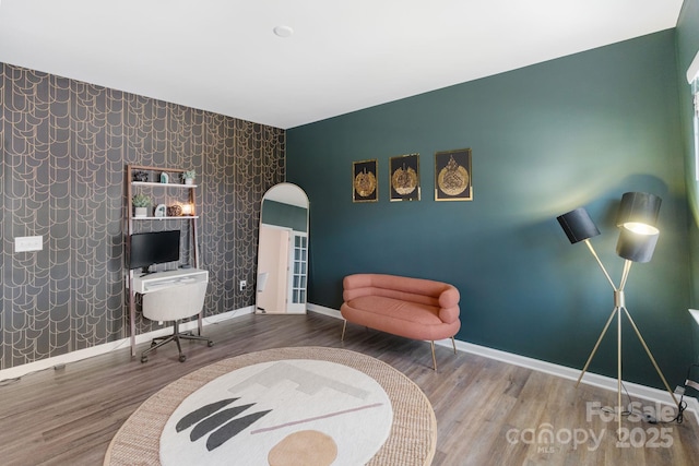 1001 Linn Cv, Waxhaw, NC 28173 - sitting room with an accent wall, baseboards, wallpapered walls, wood finished floors, and arched walkways