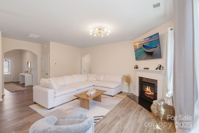 1001 Linn Cv, Waxhaw, NC 28173 - living area featuring arched walkways, wood finished floors, a glass covered fireplace, a chandelier, and baseboards