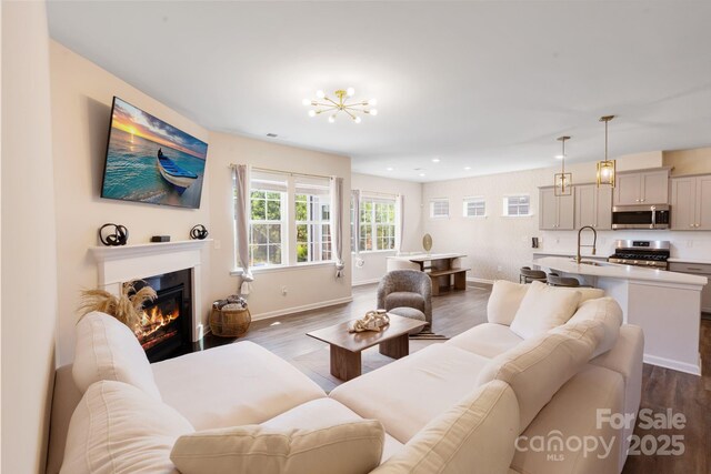 1001 Linn Cv, Waxhaw, NC 28173 - living area with dark wood-type flooring, a glass covered fireplace, recessed lighting, baseboards, and a chandelier