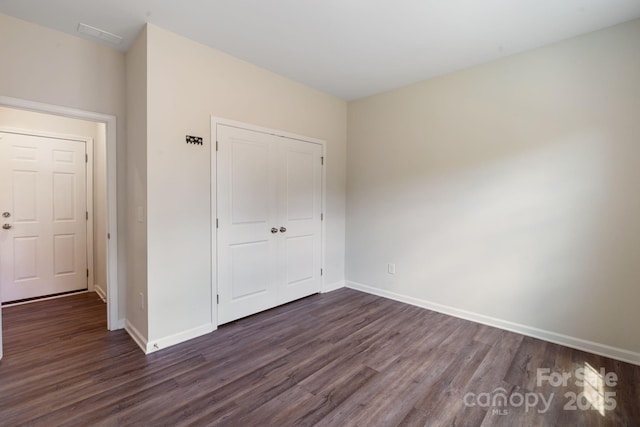 1001 Linn Cv, Waxhaw, NC 28173 - unfurnished bedroom featuring dark wood-style flooring, a closet, and baseboards