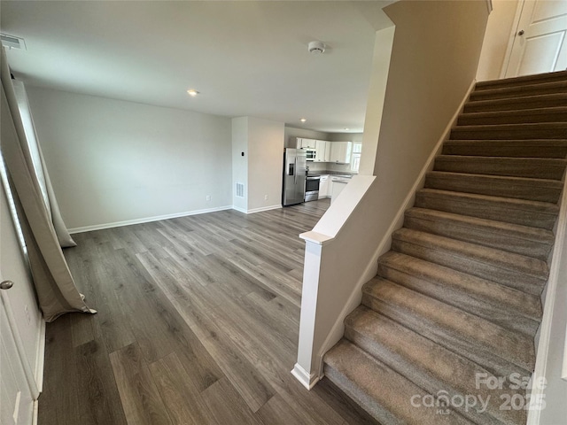stairs with wood finished floors, baseboards, and recessed lighting