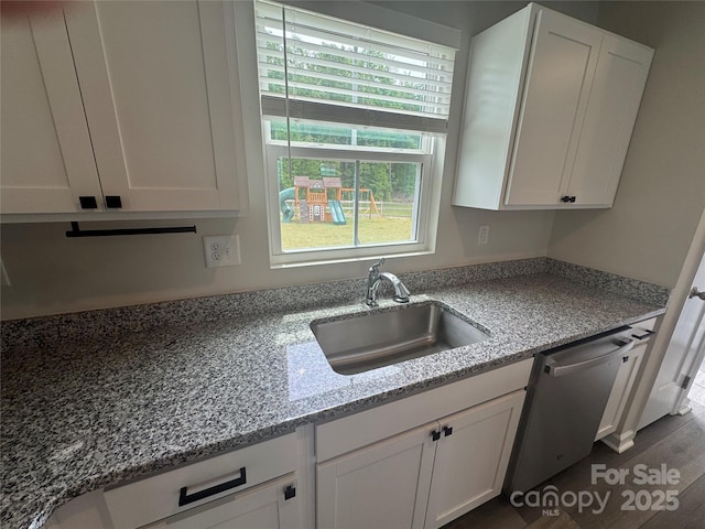 kitchen with a sink, white cabinetry, stainless steel dishwasher, and light stone countertops