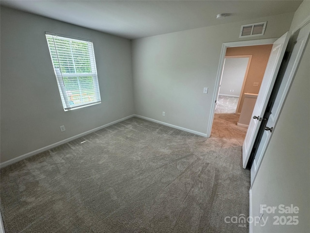 carpeted empty room featuring baseboards and a smoke detector