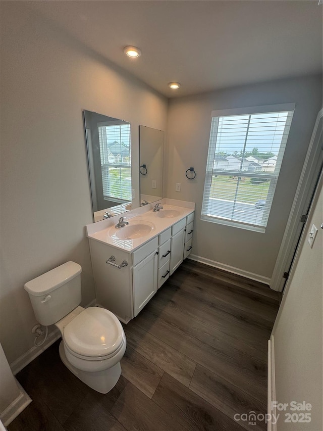 full bath with toilet, double vanity, wood finished floors, and recessed lighting