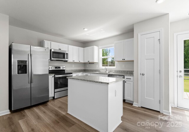 110 Browband St, Troutman, NC 28166 - kitchen featuring appliances with stainless steel finishes, a center island, wood finished floors, white cabinetry, and a sink