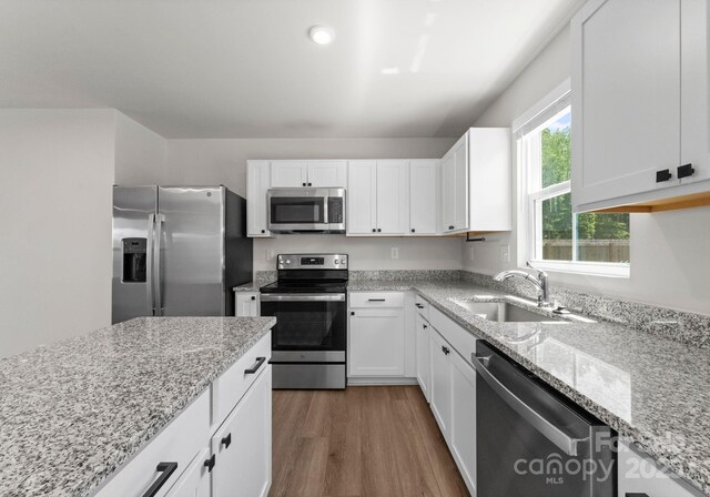 110 Browband St, Troutman, NC 28166 - kitchen featuring stainless steel appliances, a sink, wood finished floors, white cabinets, and light stone countertops