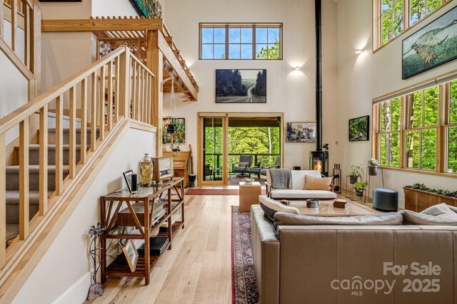 7 Bee Balm Way, Asheville, NC 28804 - living room with a towering ceiling, stairs, a wood stove, wood finished floors, and healthy amount of natural light