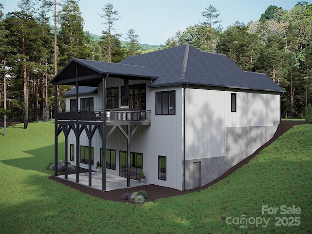 rear view of property featuring a patio area, a yard, a shingled roof, and a balcony